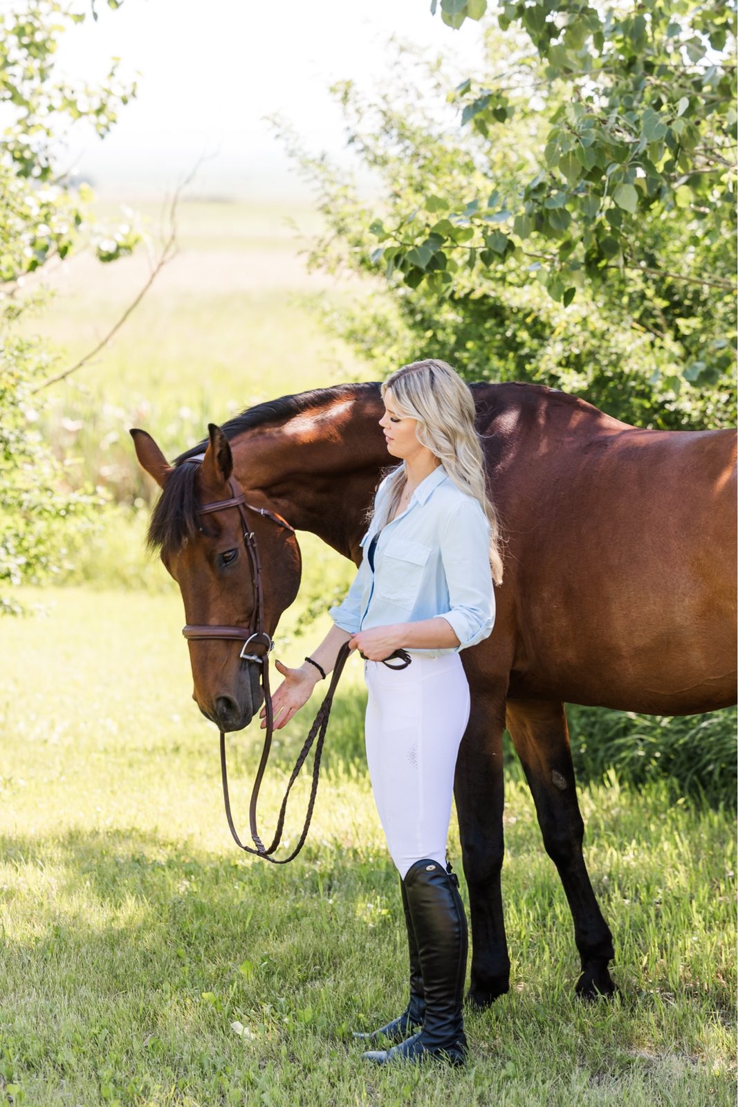 Founder of MKM Sport Horses leading a bay sport horse down a tree-lined path
