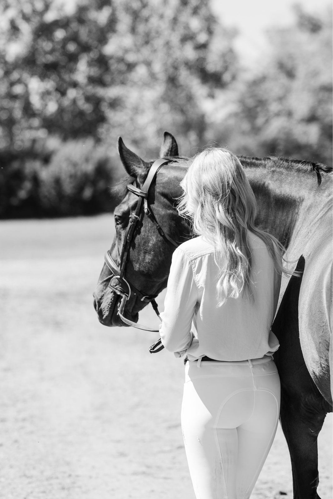Founder of MKM Sport Horses standing with a bay sport horse, black and white portrait